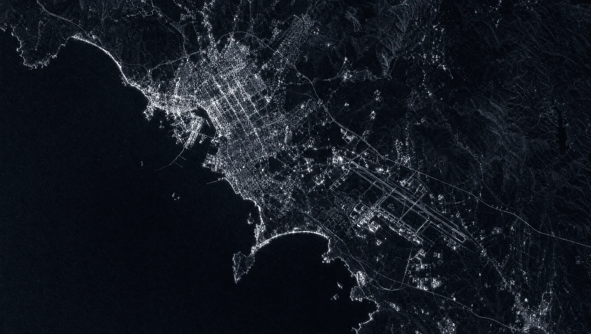 Synthetic aperture radar view of a coastal region with airfield and city returns